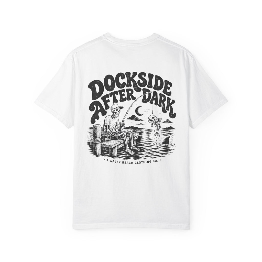 A white short-sleeve t-shirt with a large black graphic print on the back. The graphic features the text 'DOCKSIDE AFTER DARK' in a stylized font above an illustration of a man fishing from a dock at night with a fish jumping out of the water.