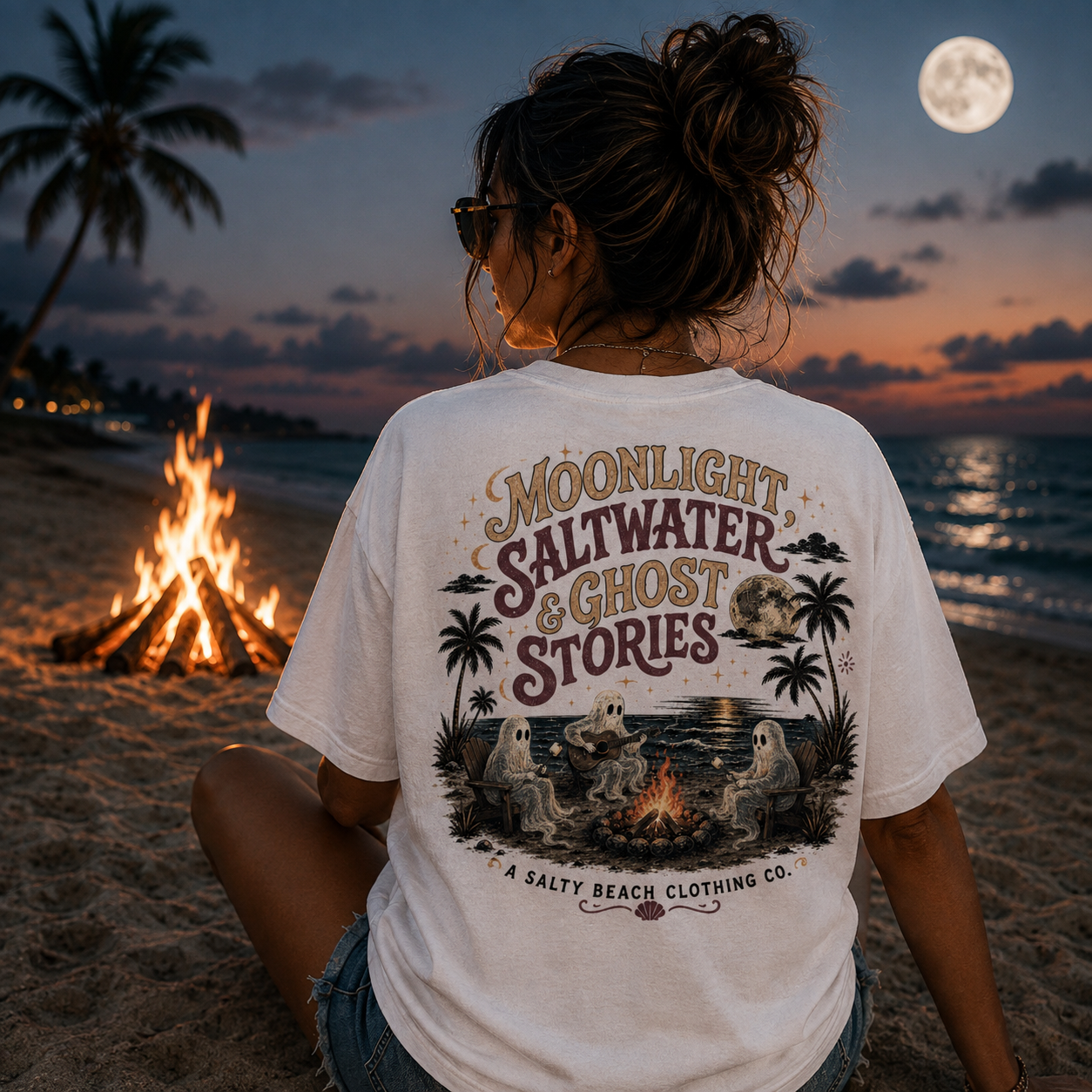 Woman wearing the Moonlight Saltwater & Ghost Stories coastal Halloween graphic tee by A Salty Beach Clothing Co.